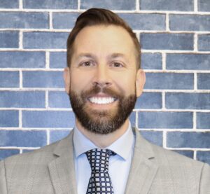 Michael Saylor stands in front of a brick building, smiling.